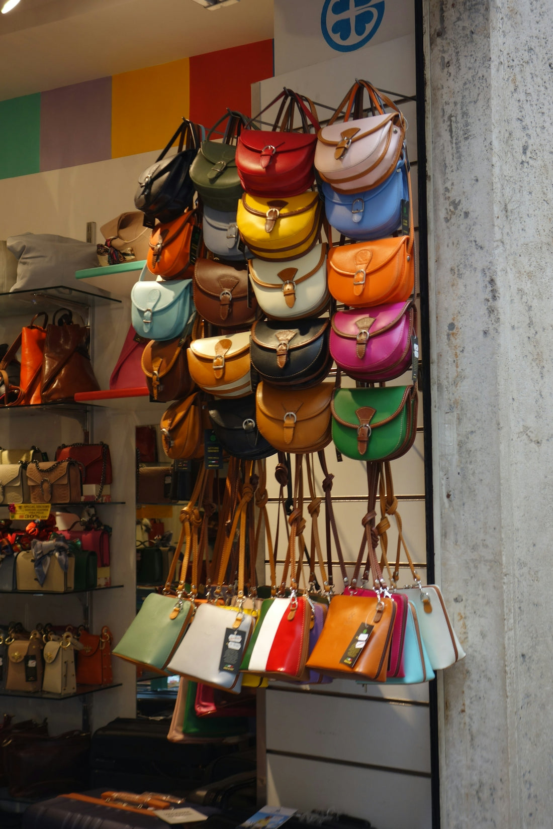 Colorful leather handbags displayed on a wall.
